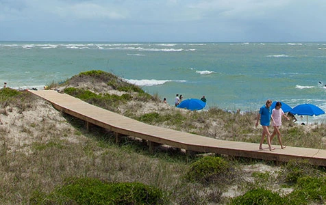 People walking on beachside bridge